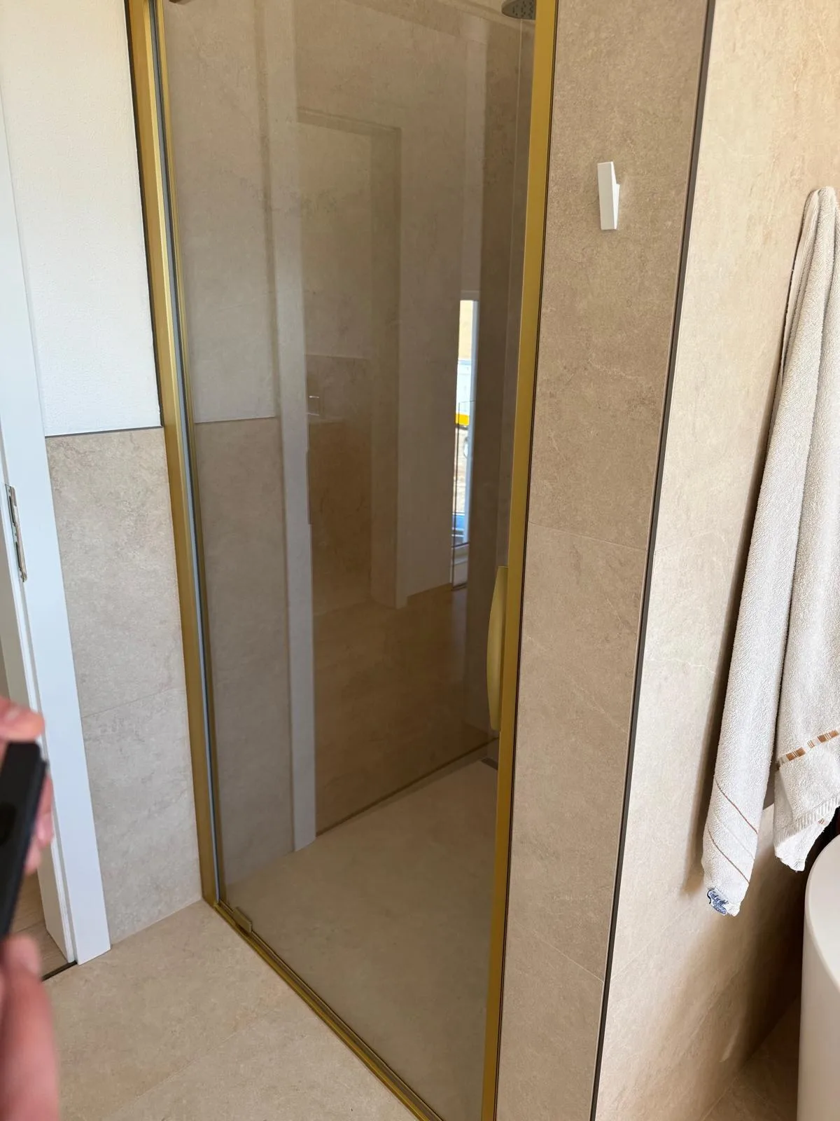 Begehbare Dusche hinter einer Glastür mit Handtüchern daneben