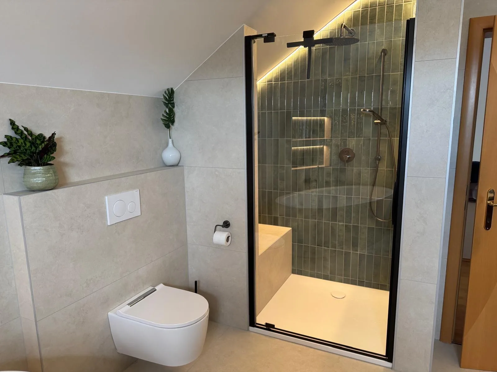 Wand-WC und begehbare Dusche hinter einer Glastür