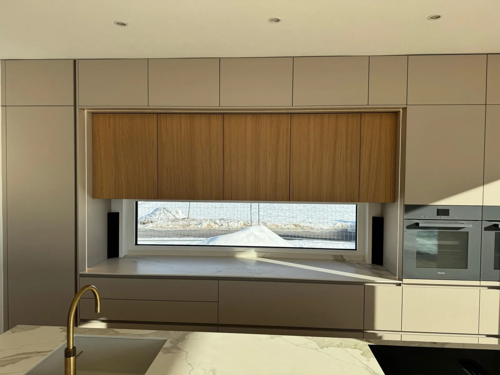 Küche mit Marmor-Arbeitsplatte, Holzrollo über dem Fenster und Einbaugeräten