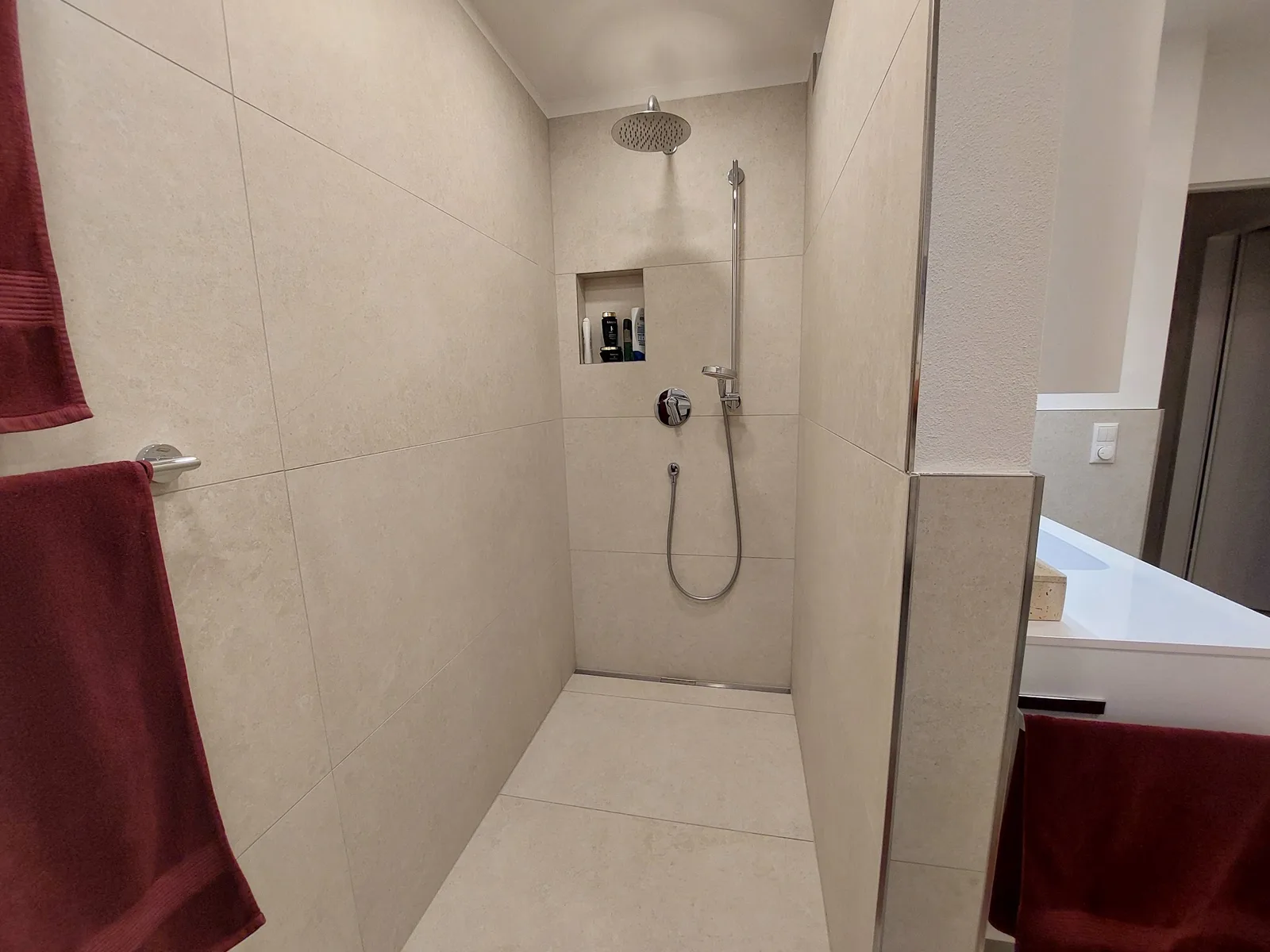 Begehbare Dusche mit Regenbrause und gefliester Ablagenische, beige Großformatfliesen